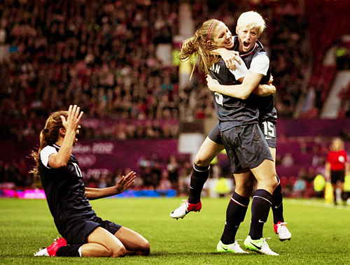 United States' Megan Rapinoe, right, celebrates with teammate Alex Morgan as Tobin Heath slides in on her knees after scoring against Canada during their semifinal women's soccer match at the 2012 London Summer Olympics, Monday, Aug. 6, 2012, at Old Trafford Stadium in Manchester, England. (AP Photo/Jon Super)